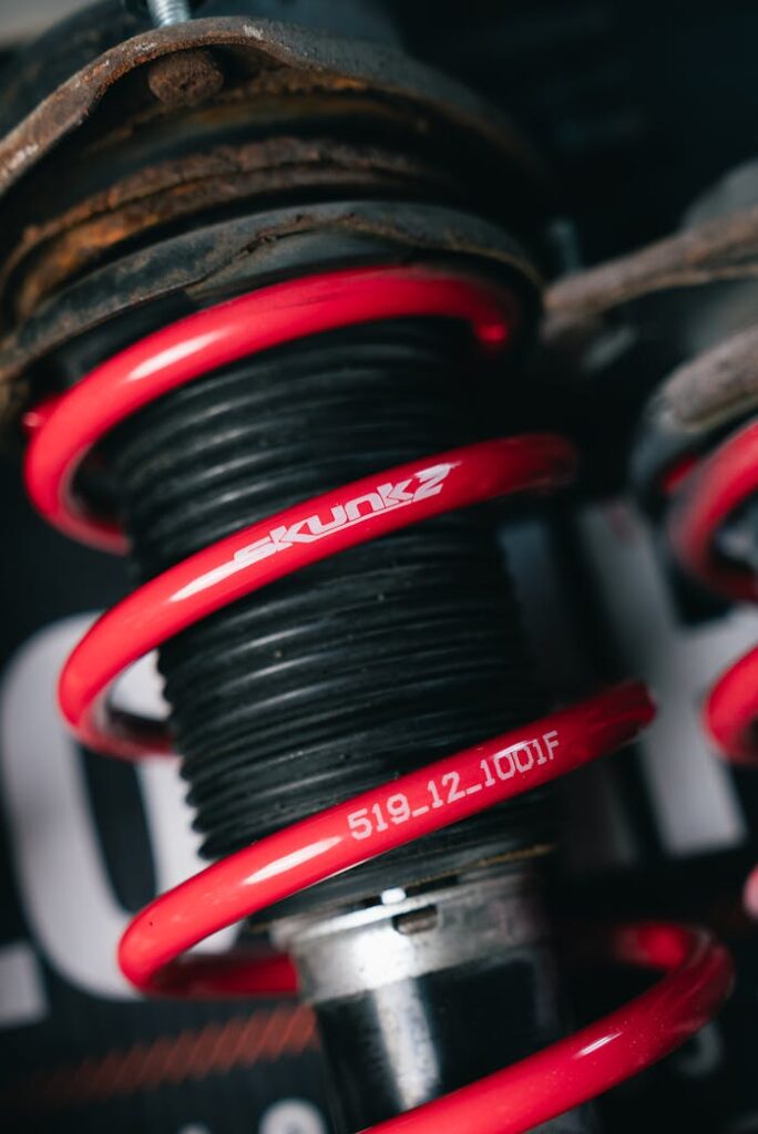 Detailed view of a red coilover suspension spring with visible branding. Automotive part.